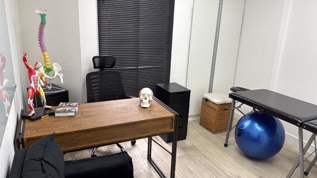 Vista ampla da sala de atendimento da Kurare com maca, mesa de orientação e equipamentos