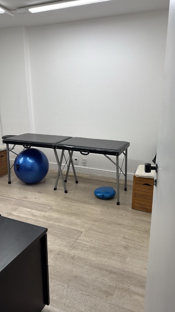 Sala com maca de atendimento e bola suíça para exercícios terapêuticos